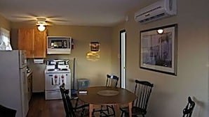 A compact kitchen with a dining table, chairs, a microwave, and an oven.