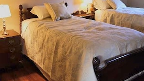 A bedroom with two single beds, a nightstand with a lamp, and a dresser.