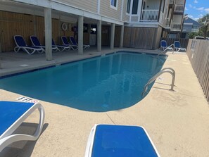 A swimming pool with lounge chairs, a lifeguard stand, and a wooden fence. - Windy Village Oceanfront…August Weeks Available at Reduced Rate…Recent Upgrades  (North Myrtle Beach)