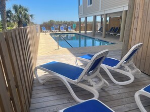 A poolside area with lounge chairs and a wooden deck.