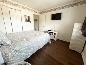 A bedroom with a bed, a television, a small side table, and a wardrobe. - Windy Village Oceanfront…August Weeks Available at Reduced Rate…Recent Upgrades  (North Myrtle Beach)