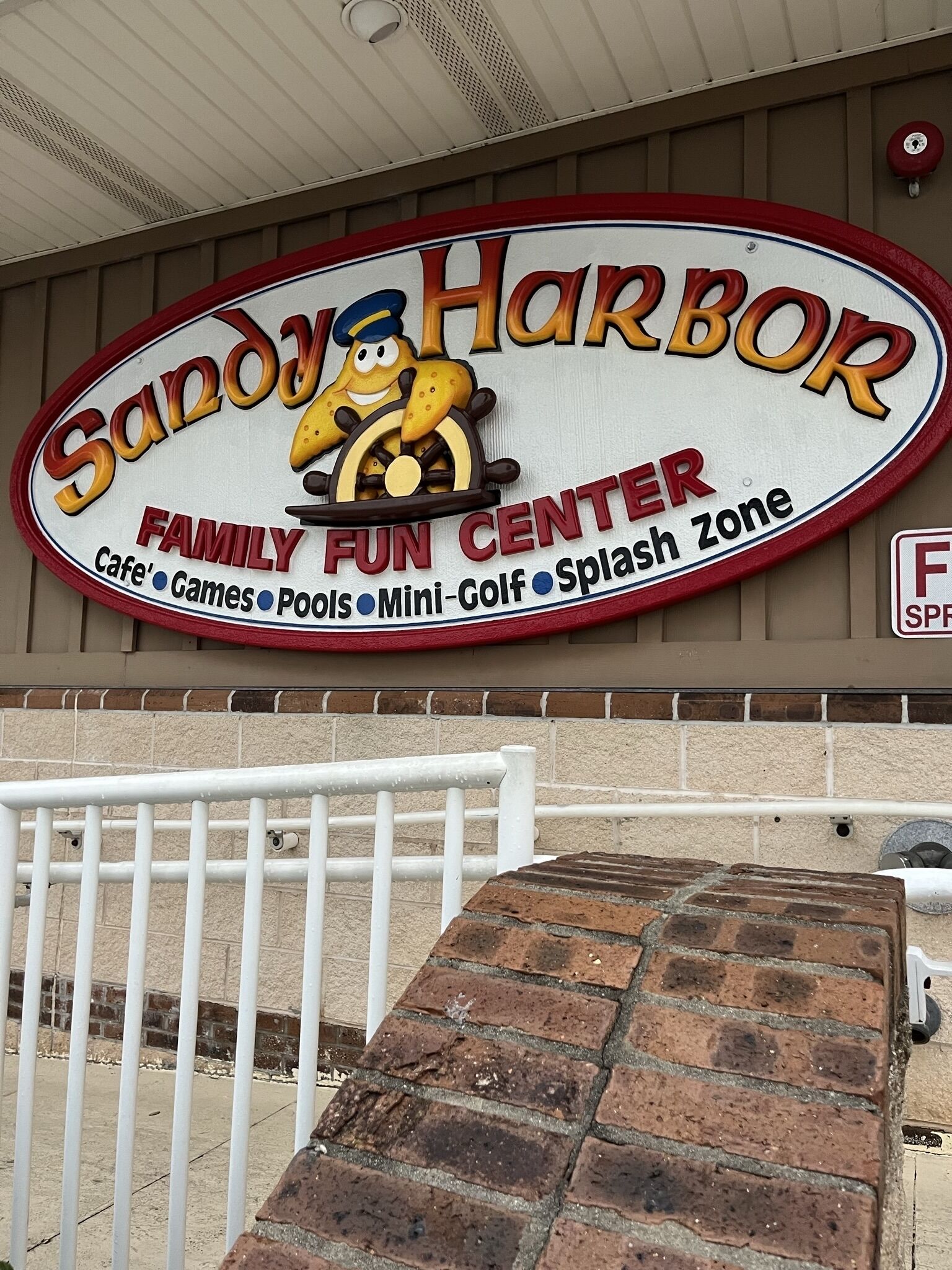 Placa do Sandy Harbor Family Fun Center com comodidades como jogos, piscinas, mini golfe e área de splash.