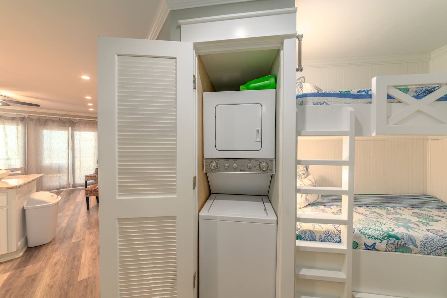 A compact room with a built-in washer and dryer, a bunk bed, and a small seating area with a table and chairs.