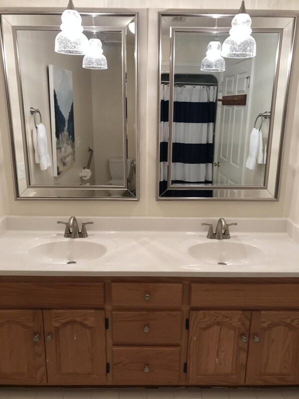 A bathroom with two sinks, wooden cabinets, and a large mirror above each sink.