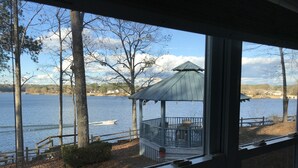 A lakeside view with a gazebo, wooden deck, and a boat on the water.