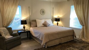 A bedroom with a bed, two bedside tables with lamps, a chair, and a large rug.