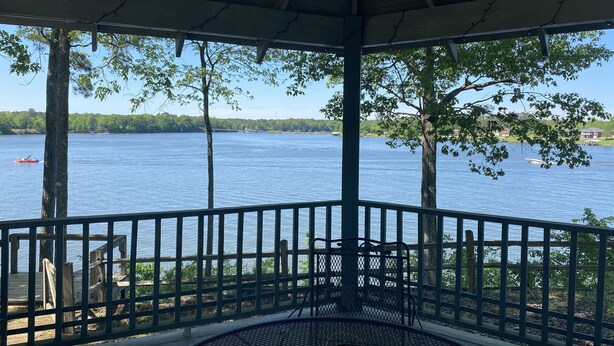 A covered outdoor seating area with a view of a lake and boats.