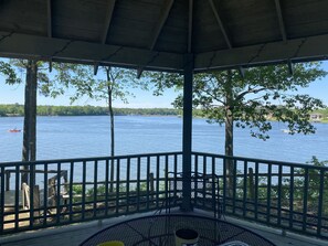 A covered outdoor seating area with a view of a lake and boats.