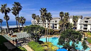 A resort with multiple-story buildings, a swimming pool, and palm trees.