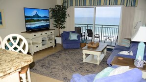 Ein Wohnzimmer mit Fernseher, einer Couch, einem Couchtisch und Meerblick.