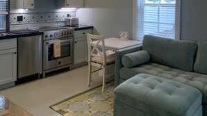 Une cuisine moderne avec des armoires blanches, une cuisinière en acier inoxydable et un ventilateur de plafond.