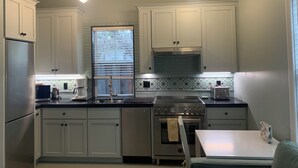 Une cuisine moderne avec des armoires blanches, des appareils en acier inoxydable et des luminaires suspendus.