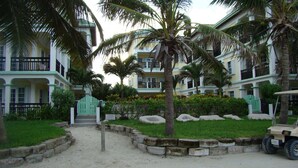 Un resort con edificios de varios pisos, palmeras y un carrito de golf.