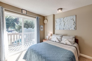 Relax in this serene hotel room featuring a large bed with a cozy bedspread and a balcony with a view of the outdoors.