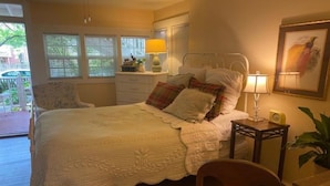 Une chambre à coucher avec un lit, une table de chevet, une chaise et une fenêtre avec des stores.