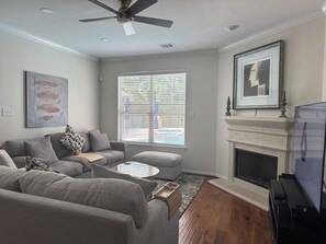 A living room with a grey sofa, a coffee table, a fireplace, and a television. - Nice Family Fr. WalMart and HEB & Wallgreens Walking, Iron Man. 3 Nights Minimum (The Woodlands)