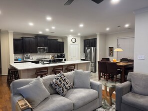 A modern kitchen with dark cabinets, stainless steel appliances, and a white island. - Nice Family Fr. WalMart and HEB & Wallgreens Walking, Iron Man. 3 Nights Minimum (The Woodlands)