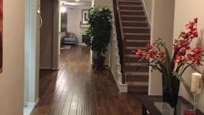 A wooden-floored hallway with a staircase, a potted plant, and a vase with flowers. - Nice Family Friendly, WalMart and HEB & Wallgreens Walking, Iron Man. (The Woodlands)
