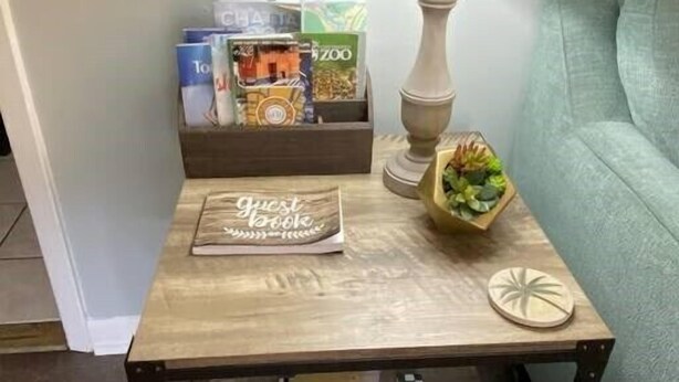 A small wooden side table with a lamp, a guest book, and a small plant.