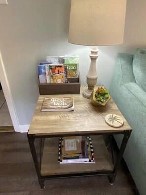 A small wooden side table with a lamp, a guest book, and a small plant.