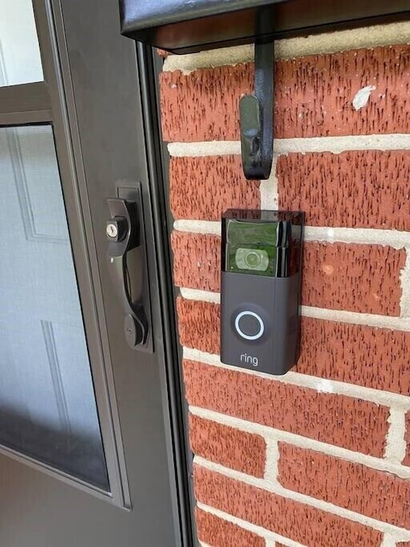 A door with a keyhole and a doorbell mounted on a brick wall.