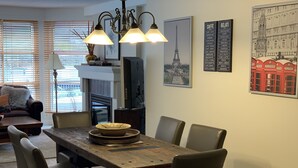 A dining area with a wooden table, chairs, and a chandelier. There are framed pictures on the walls, including one of the Eiffel Tower. - Carv'em or Park'em at Our Ski-in/Ski-out Condo in Woodrun (Whistler)