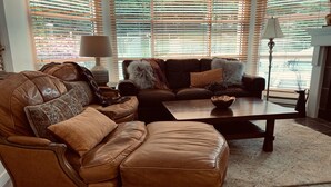 A living room with a brown leather sofa, a matching armchair, and a coffee table. - Carv'em or Park'em at Our Ski-in/Ski-out Condo in Woodrun (Whistler)