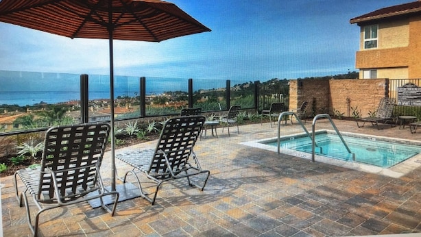 A poolside area with lounge chairs and an umbrella, overlooking a scenic view. - Beach Walk to Salt Creek Beach for Surf and Sun - Air Conditioned STR15-0392 (Dana Point)