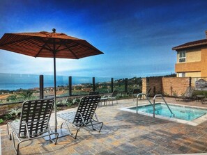 A poolside area with lounge chairs and an umbrella, overlooking a scenic view. - Beach Walk to Salt Creek Beach for Surf and Sun - Air Conditioned STR15-0392 (Dana Point)