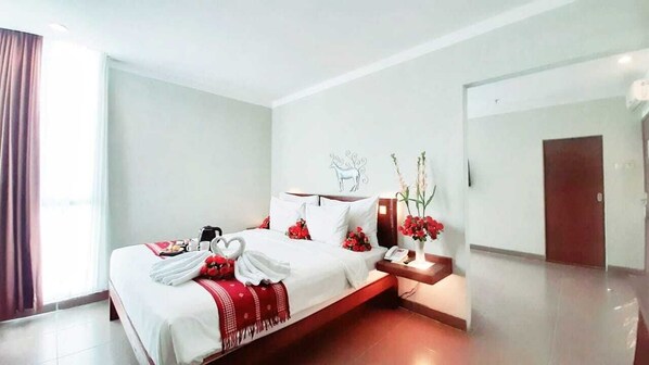 Una habitación de hotel con una cama, una mesita de noche, un espejo y una puerta.