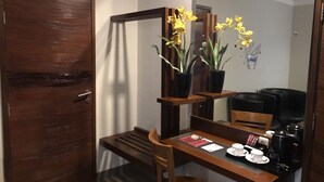 Una mesa de comedor de madera con una silla, una cafetera y una planta en maceta con flores amarillas.