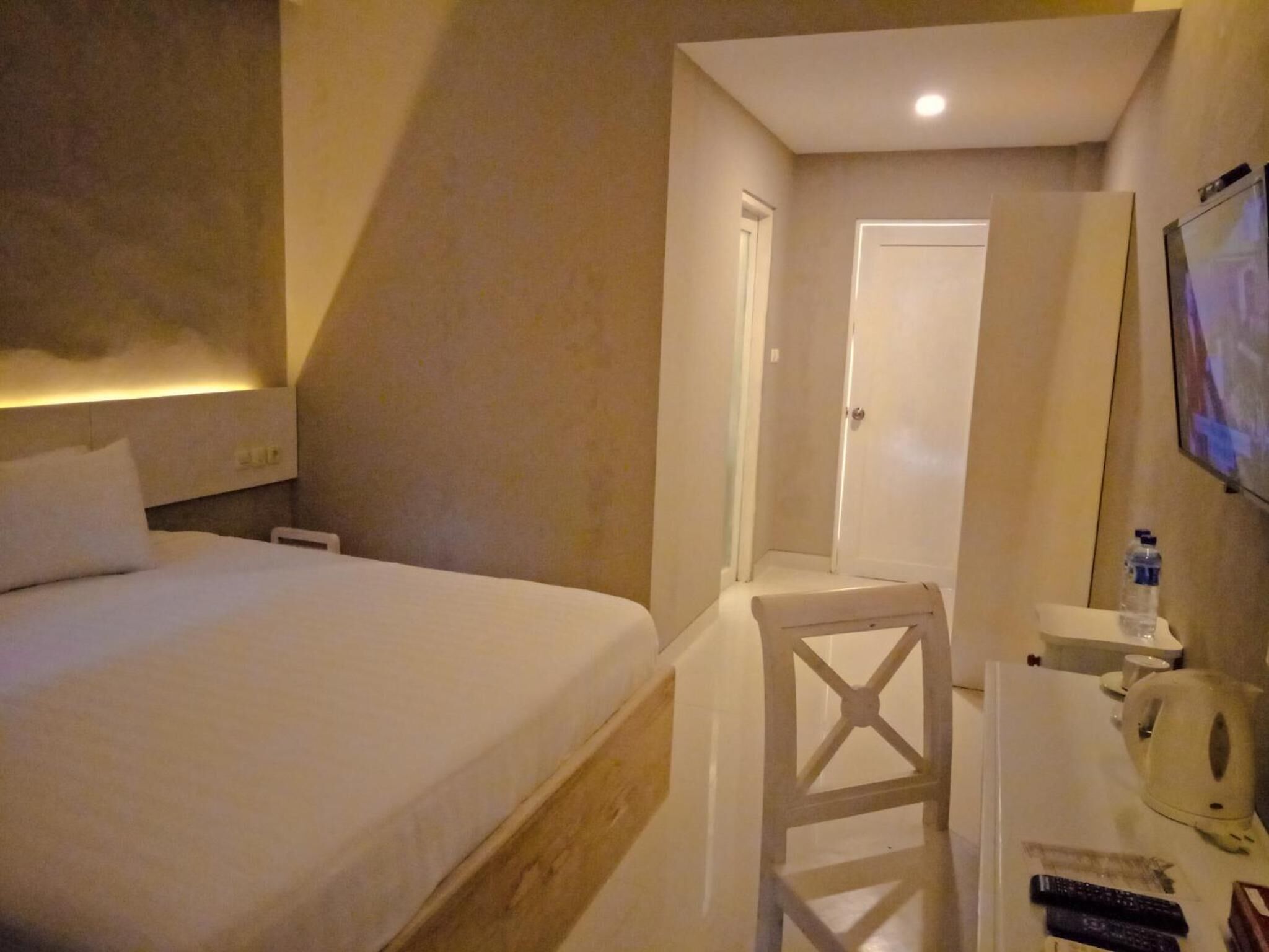 Une chambre d’hôtel comprenant un lit, un bureau avec une chaise, une télévision et une porte donnant sur une autre pièce.