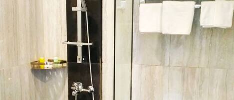 A modern bathroom with a glass-enclosed shower, a toilet, and a towel rack.