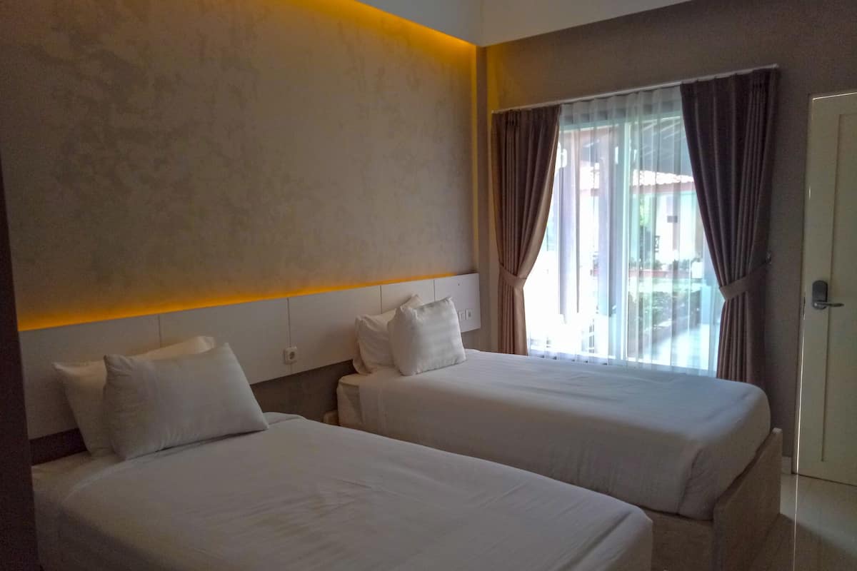 Een hotelkamer met twee bedden, een groot raam met gordijnen en een modern hoofdeinde.