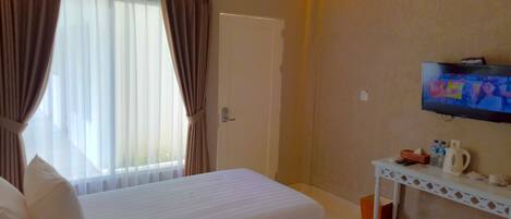 A hotel room with two beds, a TV, a small table with toiletries, and a window with curtains.