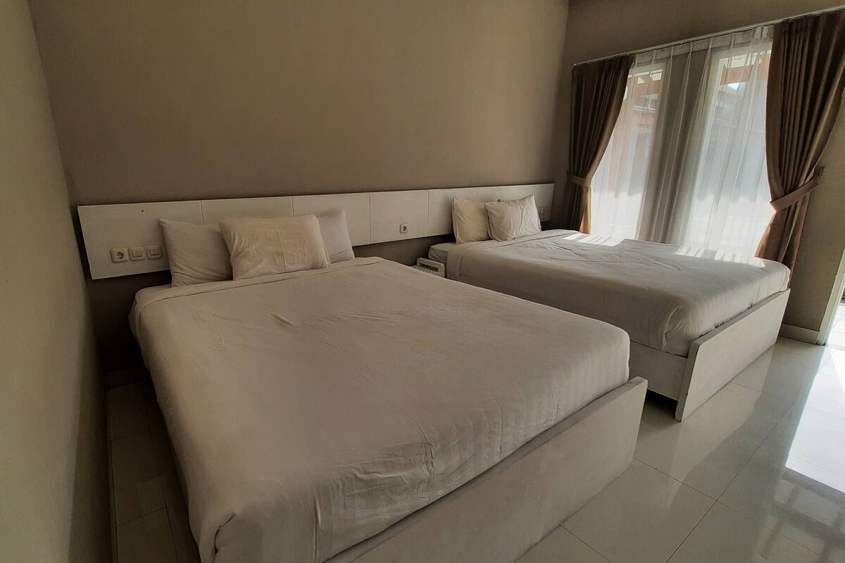 Een hotelkamer met twee bedden, een hoofdeinde en uitzicht op zee door het raam.