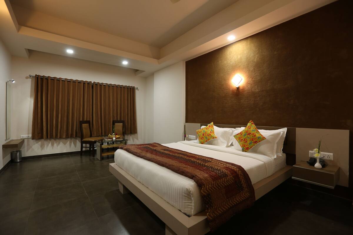 A modern hotel room with a large bed, a desk, and a chair.