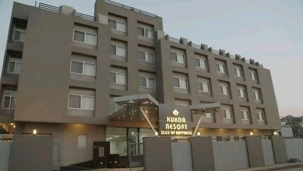 Un hotel de varios pisos llamado Kukda Resort, con un diseño moderno, que presenta una entrada destacada y un cartel.