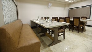 Una sala de conferencias con una larga mesa, sillas, un sofá y una pantalla para proyector.