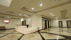 A spacious lobby with a reception desk, a flat-screen TV, and a modern ceiling design. - Kukda Resort Chittorgarh (Chittorgarh)