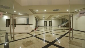 A spacious lobby with a marble floor, a reception desk, and a staircase leading to upper floors. - Kukda Resort Chittorgarh (Chittorgarh)