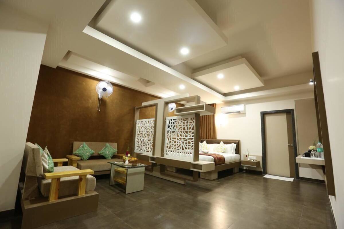 A modern hotel room with a sofa, a bed, a small table, and a decorative partition.