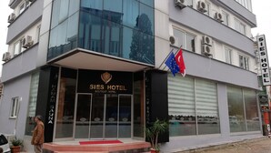 A modern hotel building with a sign reading "SIES HOTEL BOUTIQUE HOTEL" and a flag with stars. - Sies Hotel (Antalya)