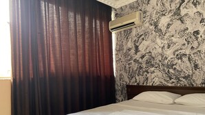 A hotel room with a bed, curtains, an air conditioning unit, and a patterned wall. - Sies Hotel (Antalya)