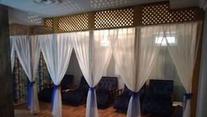 A room with a wooden floor, four dark blue armchairs, and white curtains with blue ties. - Sies Hotel (Antalya)