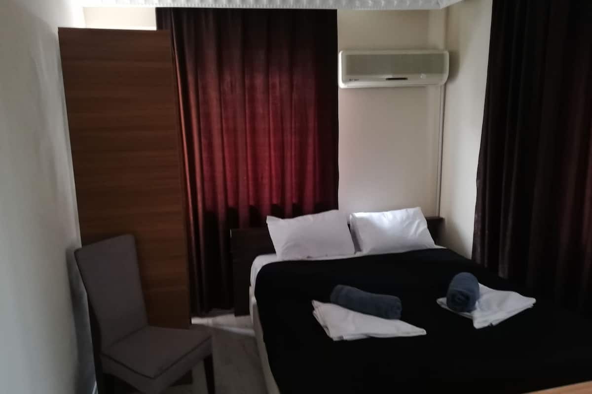 Habitación de hotel con cama, una silla, escritorio y aire acondicionado.