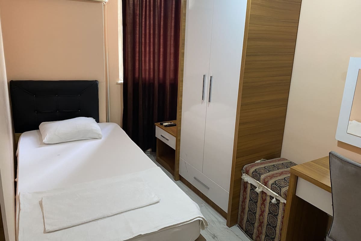Una habitación de hotel con cama, armario, escritorio y silla.