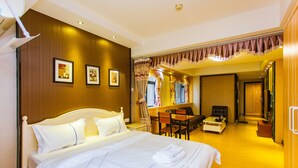 Una camera d'albergo con un letto grande, una scrivania e una sedia. Alle pareti ci sono quadri appesi e una finestra con tende.