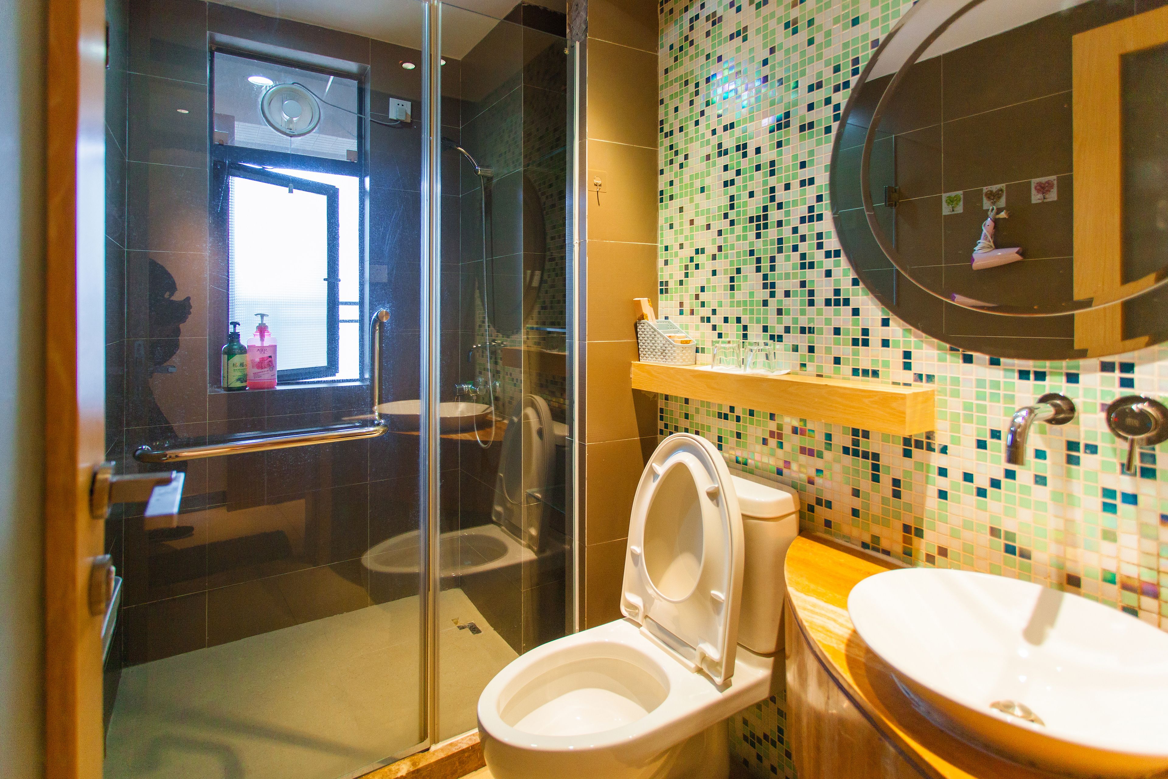 Een badkamer met een douche in een glazen cabine, een toilet en een wastafel met een houten blad.