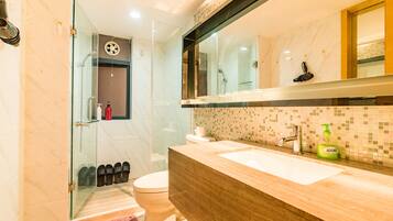 A modern bathroom with a glass shower enclosure, a wooden vanity, and a large mirror.